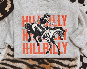 May include: A gray sweatshirt with a graphic design of a cowboy riding a horse. The text "HIGH CLASS HILLBILLY" is printed in orange on the shirt.