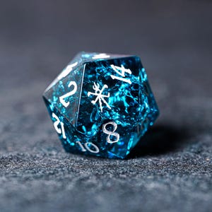 May include: A blue, iridescent, 14-sided dice with white numbers and symbols. The dice is made of glass and has a textured surface.