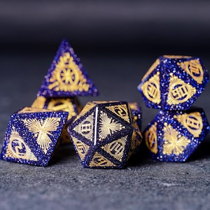 Op de afbeelding: Een set van zes blauwe en gouden dobbelstenen met een stervormig ontwerp. De dobbelstenen zijn gemaakt van een glinsterend materiaal en hebben een uniek, ingewikkeld ontwerp.