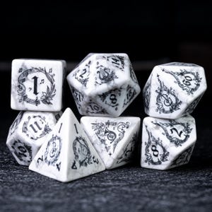 May include: Set of seven polyhedral dice with a white marble effect and black musical note designs. The dice include a D4, D6, D8, D10, D12, D20, and a percentile die. Each die features a unique number and musical motif.