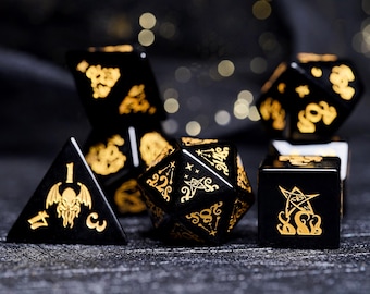 May include: A set of black and gold dice with various symbols and numbers. The dice are made of a polished black stone with gold accents.
