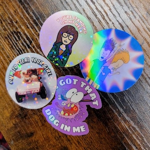 May include: A collection of four holographic stickers featuring cartoon characters and phrases. One sticker says "You're standing on my neck," another says "Omw to steal your girl," and a third says "Got that dog in me."