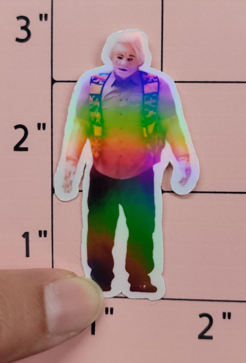 May include: A holographic sticker of a man in a button-down shirt, vest, and pants. The sticker is approximately 2 inches tall. The image has a rainbow gradient effect, with the man's face and hands in a lighter color.