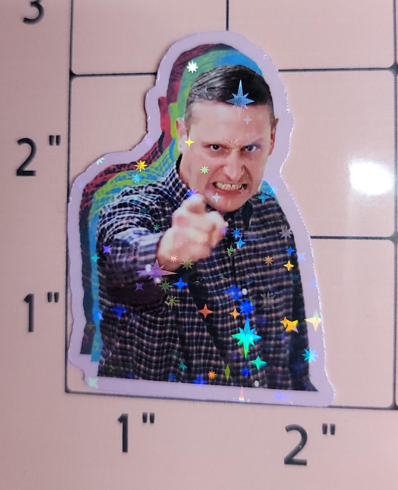 May include: Holographic sticker featuring a man pointing with an angry expression. The sticker has a layered effect with a purple outline and iridescent star accents. The man is wearing a plaid shirt.