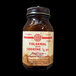 May include: A vintage amber glass medicine bottle with a dark brown screw-top lid. The off-white paper label features red text reading Tolserol with Codeine 1/8 gr., Squibb, and 100 tablets, along with a circular logo and a warning about habit-forming.