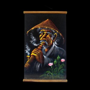 May include: A framed painting of an elderly man wearing a conical hat, smoking a long pipe. The man has a white mustache and beard. The painting is set against a black background, with pink flowers in the lower right corner.