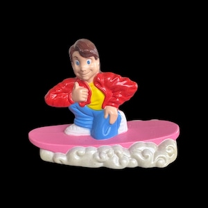May include: A figurine of a cartoon character wearing a red jacket, yellow shirt, and blue pants, giving a thumbs-up. The figure is on a pink platform with white clouds at the base. The figurine is a collectible item.
