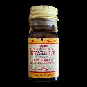 May include: A vintage amber glass bottle with a cream-colored screw cap. The label reads: 100 No. 40 POISON HYPODERMIC TABLETS CODEINE SULFATE 1/8 N.F. 1/8 gr. (0.008 Gm.) Warning May be habit forming. AX-18918-0 Lilly Eli Lilly & Co., Indianapolis, U.S.A.