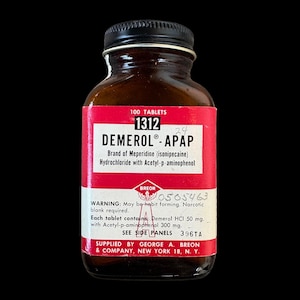 May include: A vintage amber glass medicine bottle with a black screw-top lid. The label is red and white with black text reading 100 TABLETS 1312 DEMEROL-APAP, Brand of Meperidine, Hydrochloride with Acetyl-p-aminophenol, and BREON, with handwritten numbers.