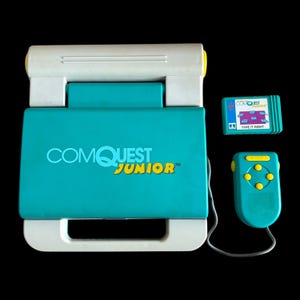 May include: A teal and white Comquest Junior electronic learning device with a matching teal game cartridge labeled Type It Right and a teal handheld controller with yellow buttons connected by a gray cord, all featuring a plastic construction.