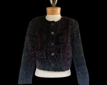 May include: A black velvet jacket with geometric gold embroidery. The jacket features a round neckline, long sleeves, and a button-down front. The design includes squares, spirals, and zigzags.