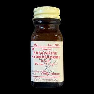 May include: A small amber glass bottle with a cream-coloured screw cap. The white label features red text reading 100 No. 1705, TABLETS PAPAVERINE HYDROCHLORIDE U.S.P. 30 mg. (1/2 gr.), Lilly POISON, XF 0498 AMX, and Eli Lilly & Co., Indianapolis, U.S.A.