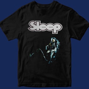 May include: Black t-shirt with a white "Sleep" logo and a black and white image of an astronaut floating in space.