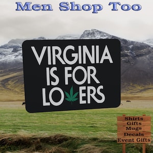 May include: A black sign with white text that reads "Virginia is for Lovers" with a green marijuana leaf in the word "Lovers". The sign is in front of a mountain range with a green grassy field in the foreground. A wooden sign in the foreground lists "Shirts, Gifts, Mugs, Decals, Event Gifts".