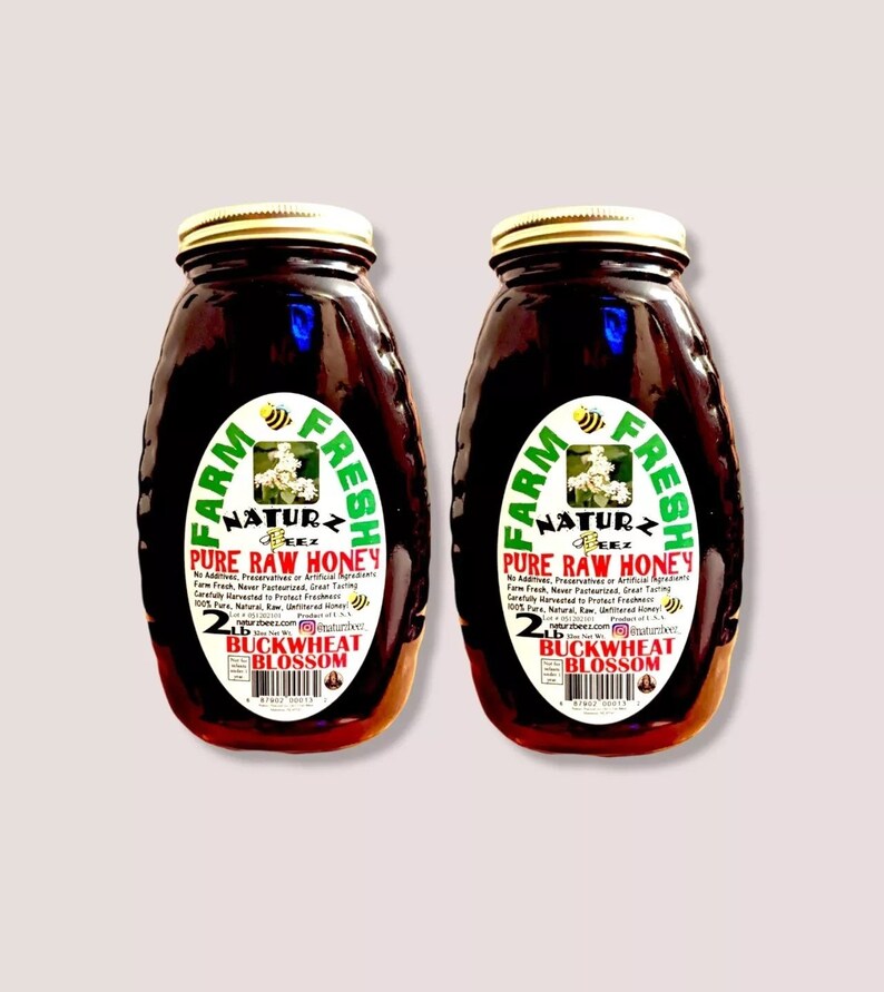 Peut inclure: Deux pots en verre de miel, chacun contenant 2 livres de miel de fleurs de sarrasin. Les pots sont &eacute;tiquet&eacute;s "Farm Fresh Naturz Beez Pure Raw Honey" et pr&eacute;sentent une &eacute;tiquette verte et blanche avec une illustration d'abeille.