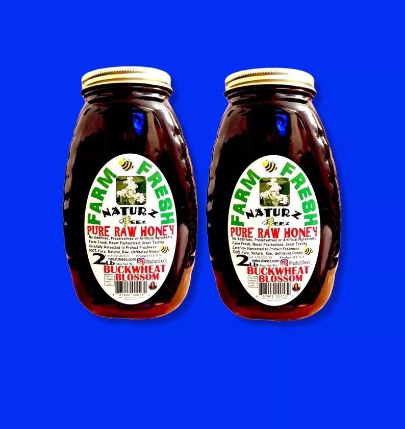 Peut inclure: Deux pots en verre de miel de fleurs de sarrasin cru. Les pots sont &eacute;tiquet&eacute;s "Farm Fresh Naturz Beez Pure Raw Honey" et pr&eacute;sentent une &eacute;tiquette verte et blanche avec une illustration d'abeille. Chaque pot contient 2 livres de miel.