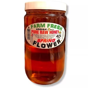 May include: A glass jar of honey labeled "Farm Fresh Naturz Beez Pure Raw Honey Spring Flower 45 oz". The honey is a light amber color.