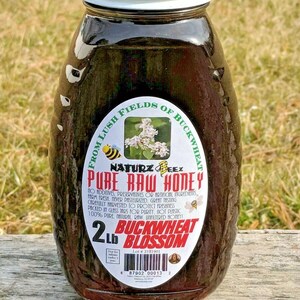 Peut inclure: Un pot en verre de miel fonc&eacute; avec un couvercle blanc. L'&eacute;tiquette indique "From Lush Fields of Buckwheat - Naturz Beez - Pure Raw Honey - 2 Lb Buckwheat Blossom".