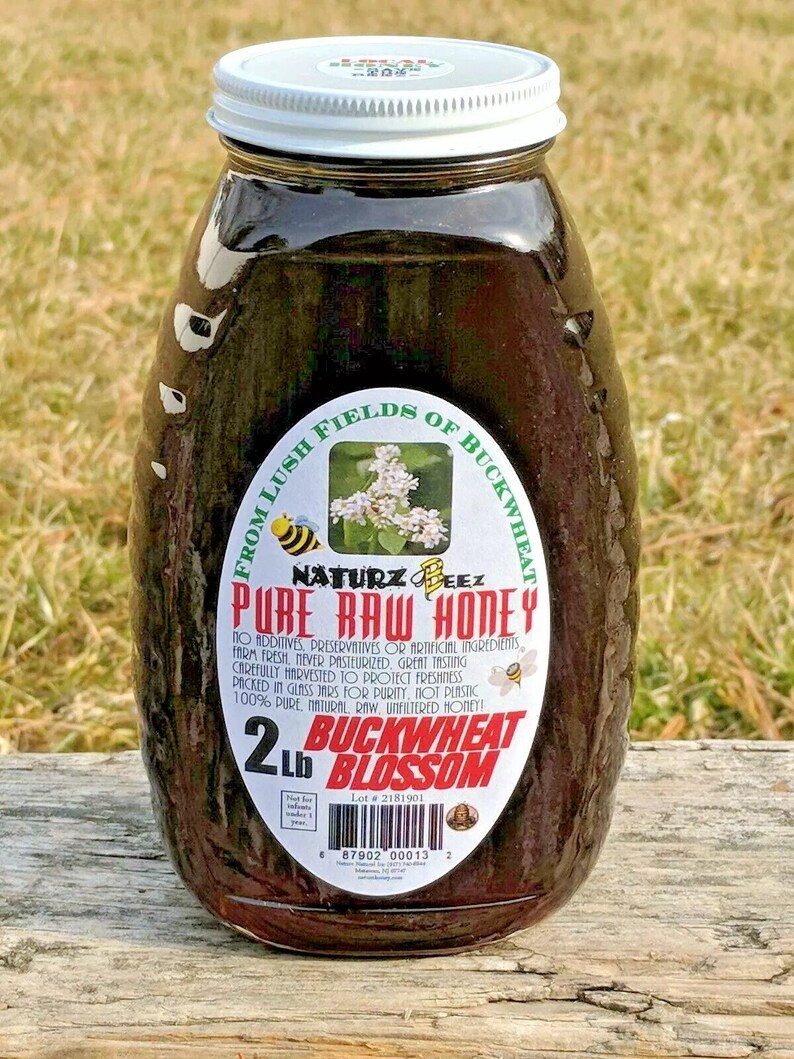 Peut inclure: Un pot en verre de miel fonc&eacute; avec un couvercle blanc. L'&eacute;tiquette indique "From Lush Fields of Buckwheat - Naturz Beez - Pure Raw Honey - 2 Lb Buckwheat Blossom".