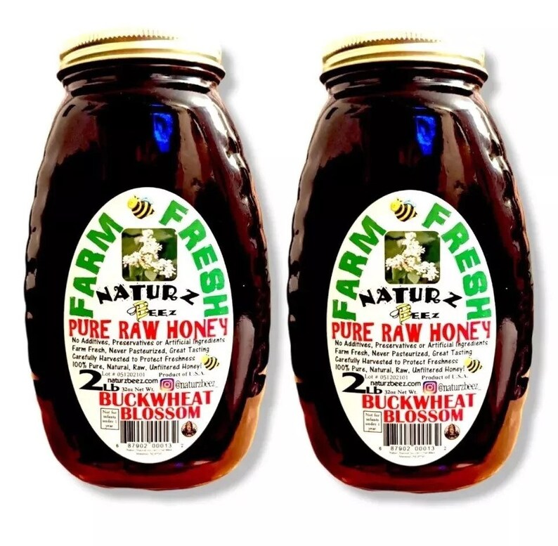 Peut inclure: Deux pots en verre de miel de sarrasin en fleurs cru, chacun &eacute;tiquet&eacute; "Farm Fresh Naturz Beez Pure Raw Honey" avec un poids net de 2 lb. Les pots sont remplis de miel fonc&eacute; et ont un couvercle dor&eacute;.
