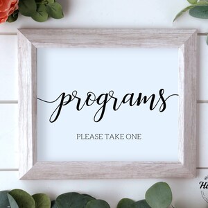 Puede incluir: Un cartel blanco con marco negro y el texto "programs" en letra cursiva. El cartel también tiene el texto "Please take one" en una fuente más pequeña.