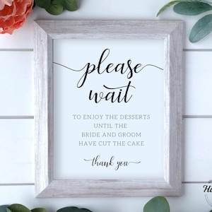 May include: A white framed sign with black text that reads "please wait to enjoy the desserts until the bride and groom have cut the cake thank you".