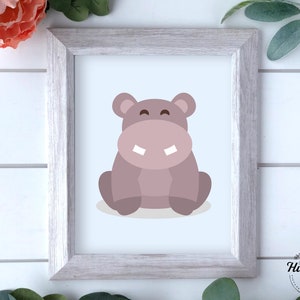May include: A printable digital download featuring a cartoon illustration of a light pink hippopotamus with a white smile. The hippo is sitting on a light blue background.