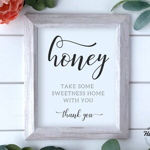 Pode incluir: Uma placa emoldurada com a palavra "honey" em elegante escrita preta. Abaixo, o texto diz "TAKE SOME SWEETNESS HOME WITH YOU" e "thank you". A moldura é cinza claro e o fundo é branco.