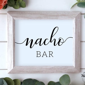 Puede incluir: Un cartel enmarcado en blanco con texto negro que dice "nacho bar" en una fuente cursiva.