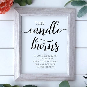 May include: White framed sign with black text that reads "This candle burns in loving memory of those who are not here today but are forever in our hearts".