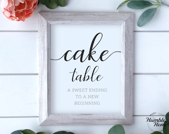May include: White framed sign with black text that reads "cake table" and "A sweet ending to a new beginning".