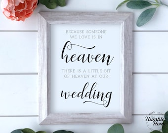 May include: A white framed sign with black text that reads "Because someone we love is in heaven, there is a little bit of heaven at our wedding".