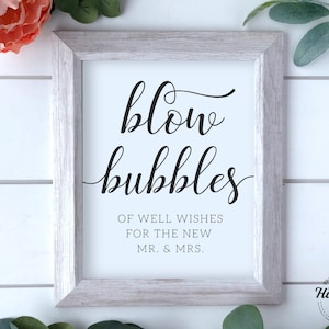 May include: White framed sign with black calligraphy that reads "blow bubbles" and "Of well wishes for the new Mr. & Mrs."