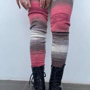 May include: A pair of pink, white, and gray striped thigh-high socks with black leather lace-up boots.