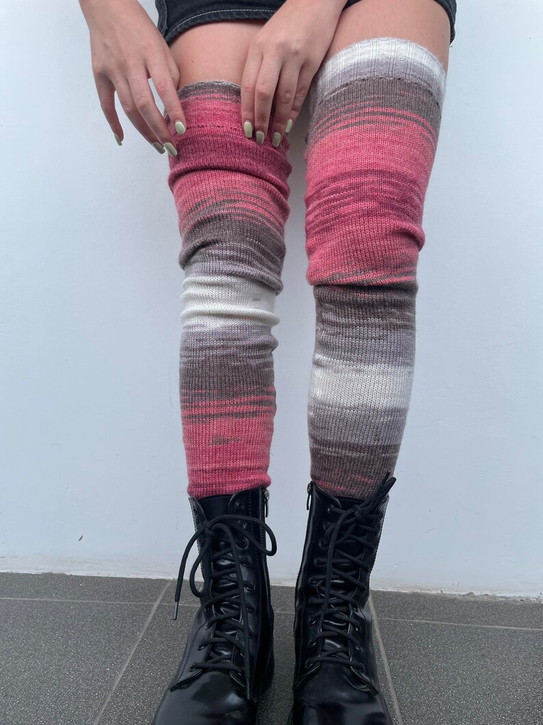 May include: A pair of pink, white, and gray striped thigh-high socks with black leather lace-up boots.