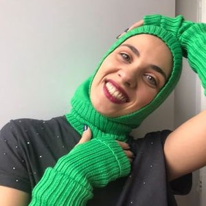 May include: A bright green knitted balaclava and matching fingerless gloves. The balaclava covers the head and neck, while the gloves extend to the elbows.
