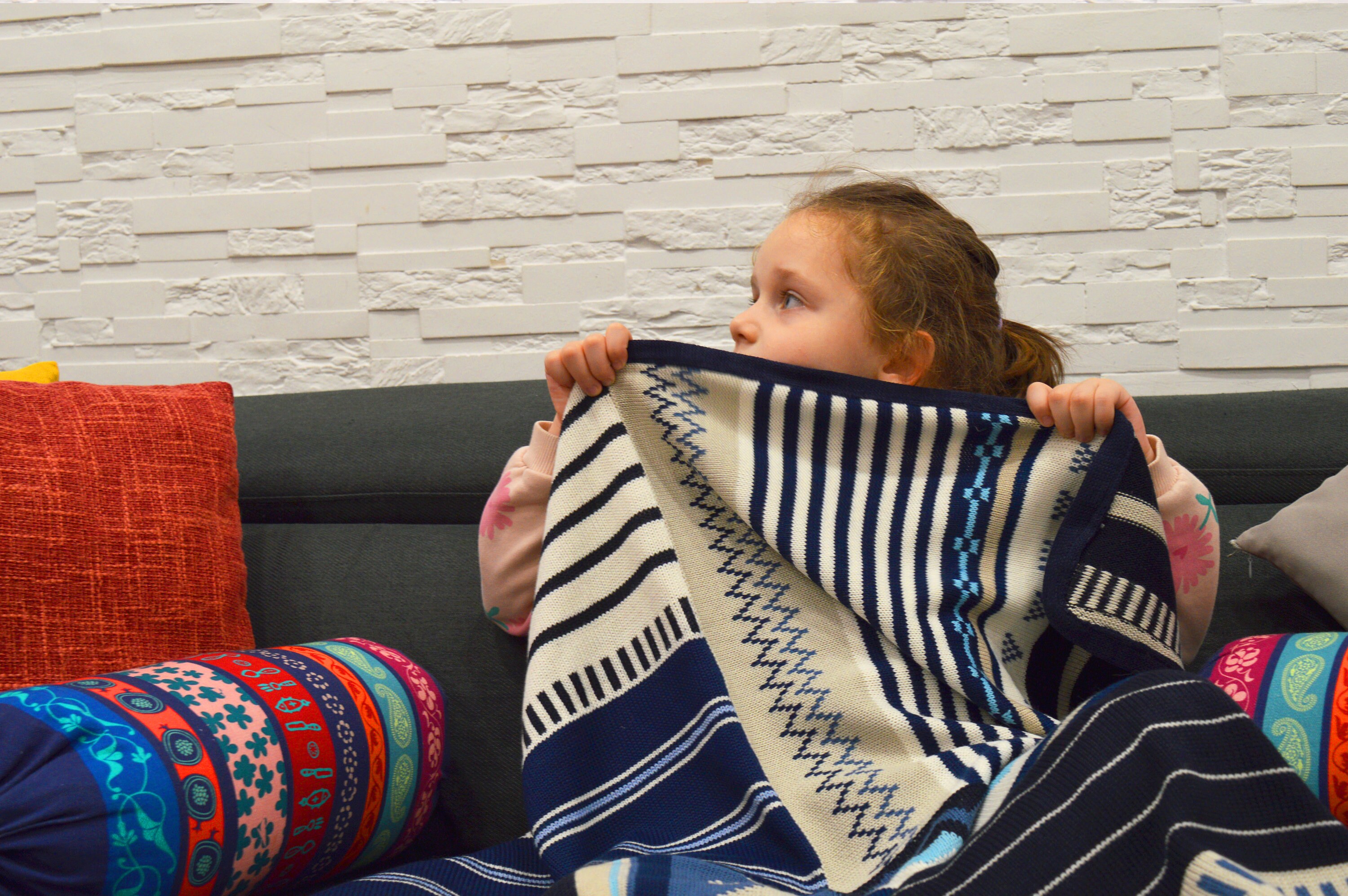 手編みのストライプ模様と装飾のある子供用ブランケット。性別を問わ