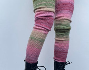 Könnte beinhalten: Ein Paar Oberschenkelsocken mit einem gestreiften Muster in Pink, Grün und Beige. Die Socken werden mit schwarzen Stiefeln getragen.