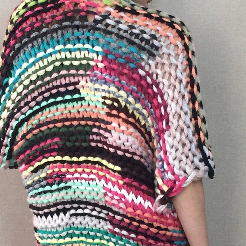 May include: A colourful, multi-coloured knitted sweater with a loose, open weave. The sweater is made with a variety of yarns in shades of pink, blue, green, yellow, orange, and black.