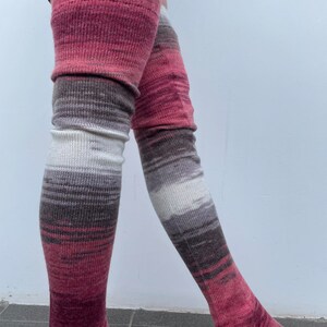May include: A pair of long, knitted thigh-high socks with a pink, white, and brown ombre pattern.