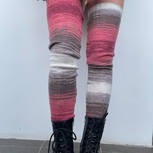 May include: A pair of pink, white, and gray thigh-high socks with a gradient pattern. The socks are made of a soft, knitted fabric and are worn with black lace-up boots.