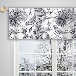 May include: A decorative window valance with a floral and bird pattern in shades of gray and white. The valance features detailed illustrations of flowers, birds, and foliage. The valance is mounted above a window with a snowy outdoor scene visible through the glass.