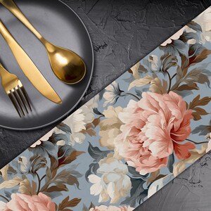 May include: A blue floral table runner with pink and white flowers. The runner is on a black surface with a black plate and gold silverware.