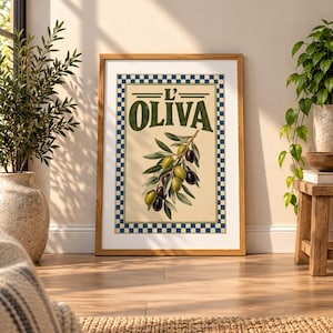 May include: A framed rectangular wall art print featuring a central illustration of an olive branch with green and black olives. The text L' OLIVA is printed in dark green above the branch, surrounded by a blue and white checkered border.