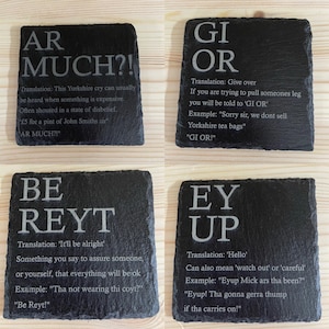 May include: Four black slate coasters with white text. Each coaster features a Yorkshire slang word and its translation. The words are "Ar Much?", "Gi Or", "Be Reyt", and "Ey Up".
