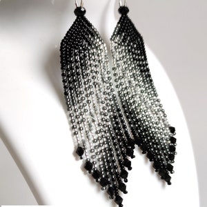 May include: A pair of long, black and silver beaded earrings with a graduated ombre effect. The earrings are made with small, faceted beads and have a teardrop shape.