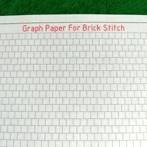 May include: A sheet of white paper featuring a grid of offset rectangular cells designed for brick stitch patterns. The text Graph Paper For Brick Stitch is printed in red at the top of the page, which is positioned against a green background.