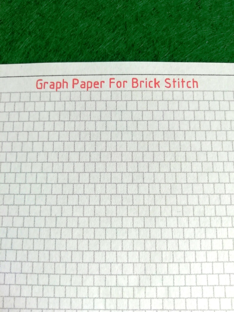 May include: A sheet of white paper featuring a grid of offset rectangular cells designed for brick stitch patterns. The text Graph Paper For Brick Stitch is printed in red at the top of the page, which is positioned against a green background.