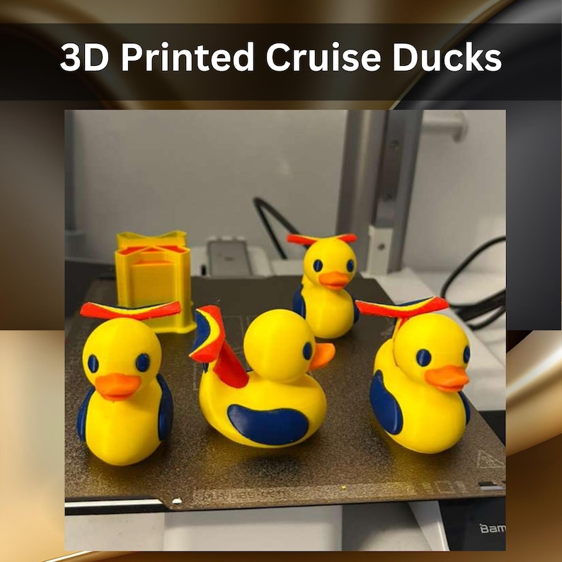 May include: Four 3D printed yellow ducks with blue wings and orange beaks, each wearing a red and blue propeller hat. The ducks are positioned on a print bed alongside a yellow rectangular object. The text 3D Printed Cruise Ducks is visible.