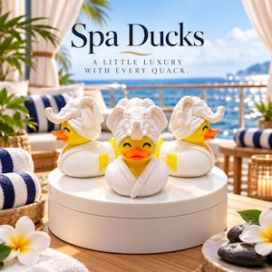 May include: Three yellow rubber ducks wearing white bathrobes and white towel head wraps. The text Spa Ducks A LITTLE LUXURY WITH EVERY QUACK is visible above the ducks. The ducks are positioned on a white circular platform.